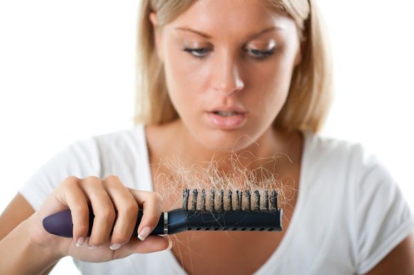 woman looks at hair in brush