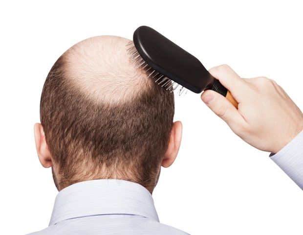 A bald head being combed with a brush